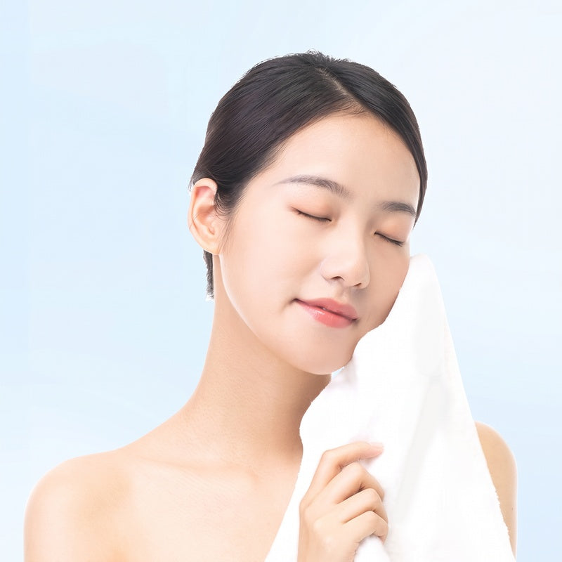 Woman drying her face with a disposable white towel